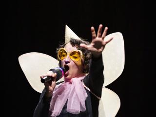 un comédien déguisé en papillon chantant